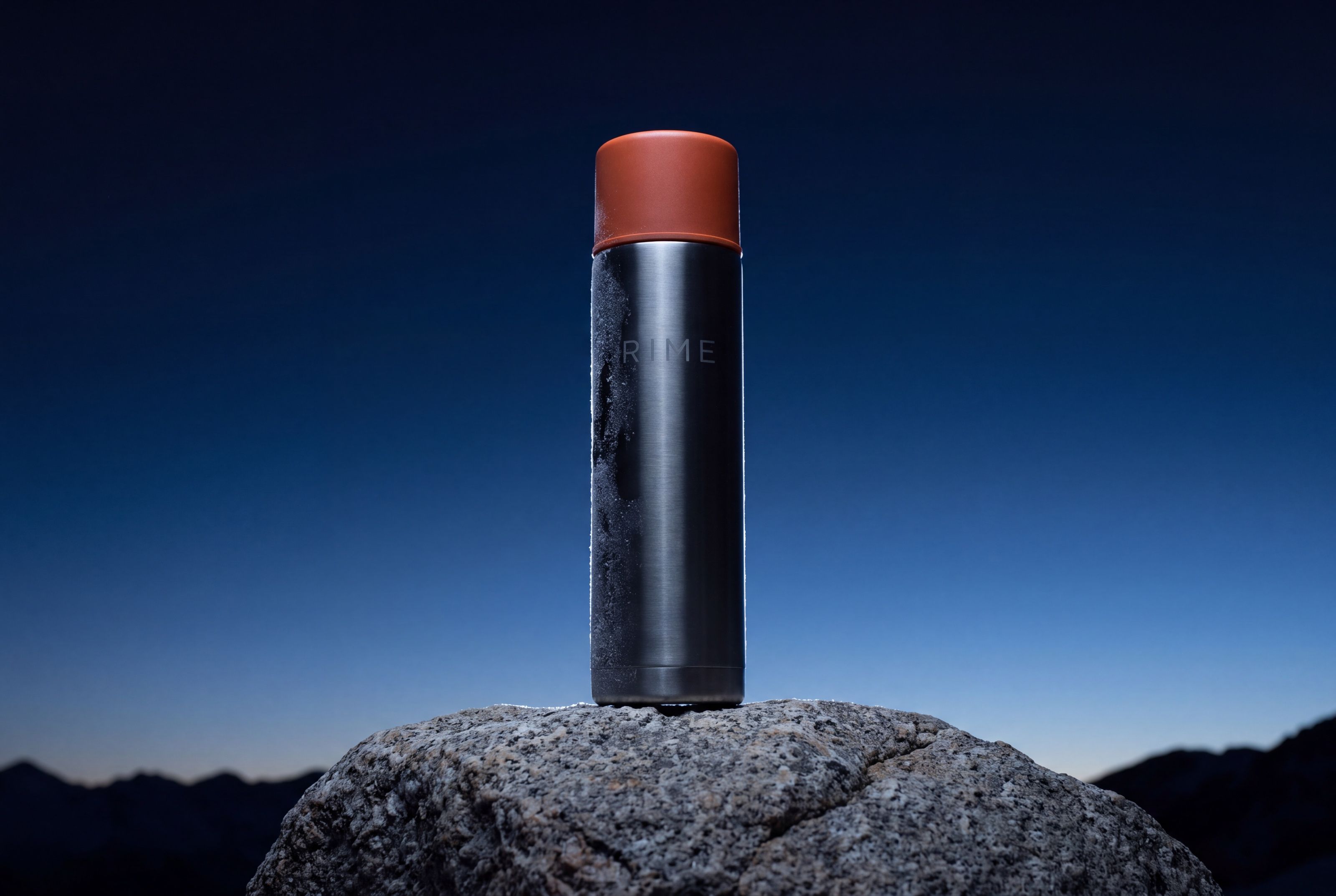 The flask in near silhouette against open sky, edged with rim light